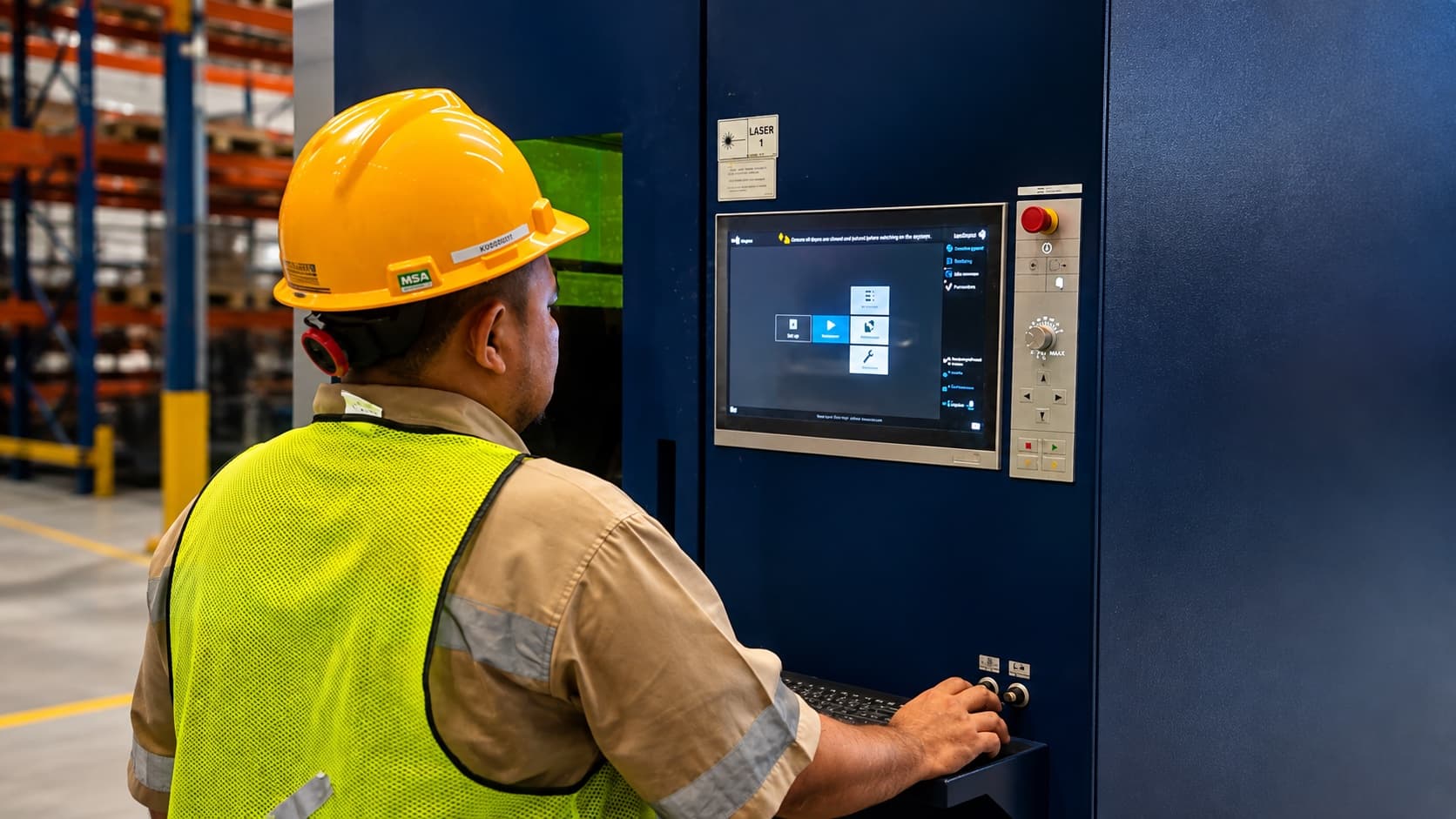 Machine operator working at a CNC control panel in safety gear